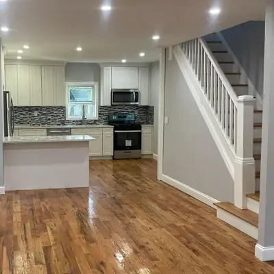 Cocina remodelada con gabinetes blancos y piso de madera